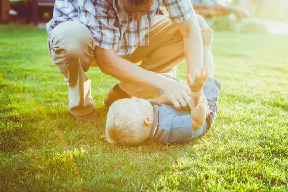 dad-tickling-baby-in-grass