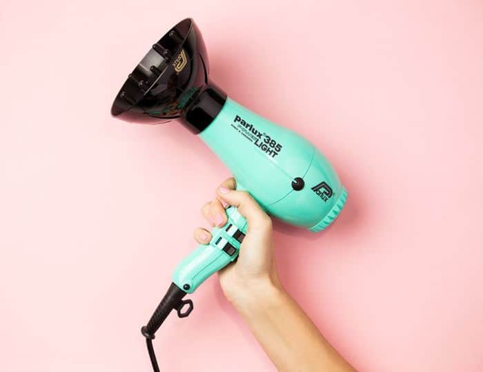 blue hairdryer held against a pink background